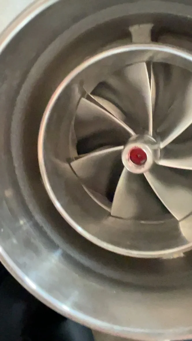 Close-up view of a turbocharger compressor wheel, showing the blades and housing.