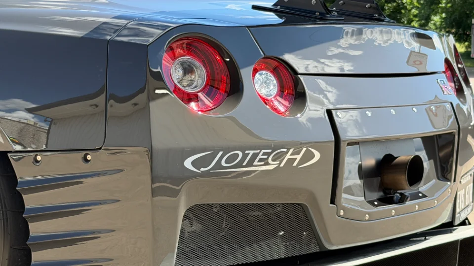Rear view of a grey Nissan GT-R with a large single exhaust tip, Jotech branding, and aftermarket diffuser.