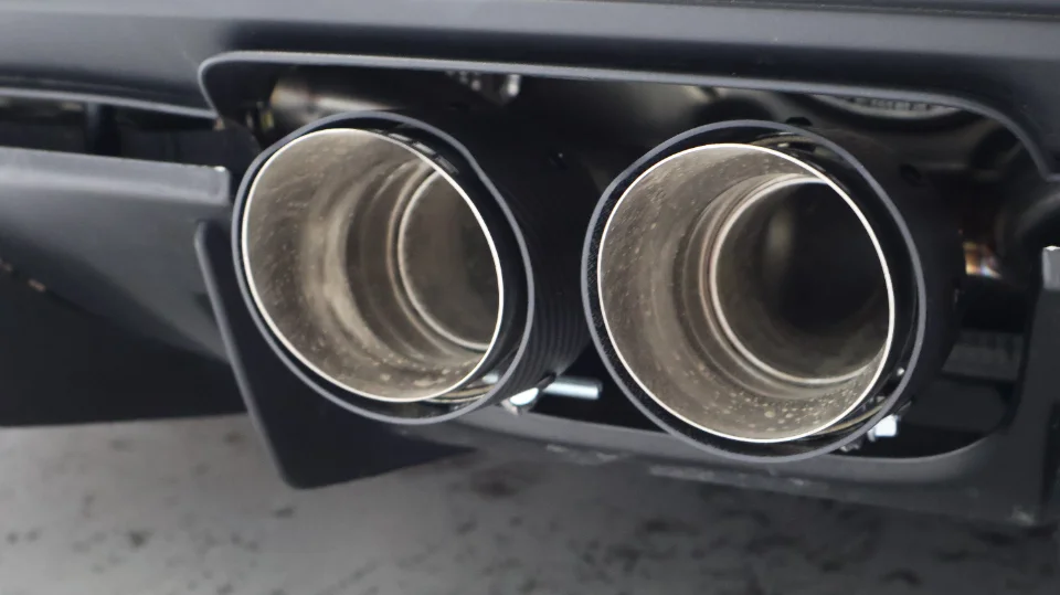 Close-up of dual stainless steel exhaust tips integrated into a performance car's rear bumper.
