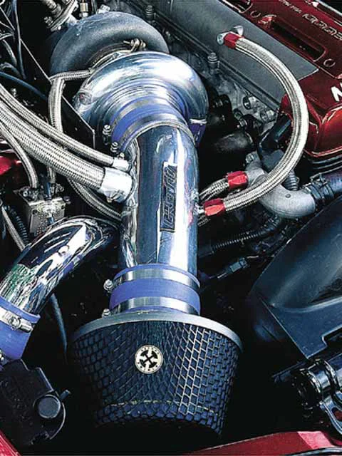 Close-up of a performance engine bay featuring a large turbocharger, chrome intake piping, and an aftermarket air filter.