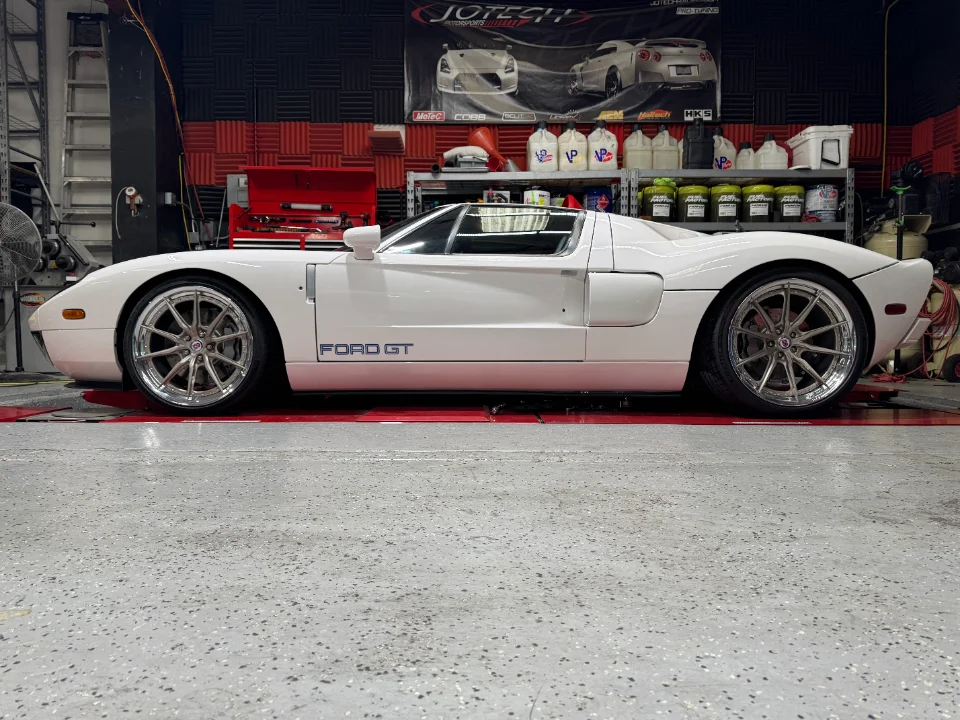 A white Ford GT with custom wheels parked inside a performance tuning shop.