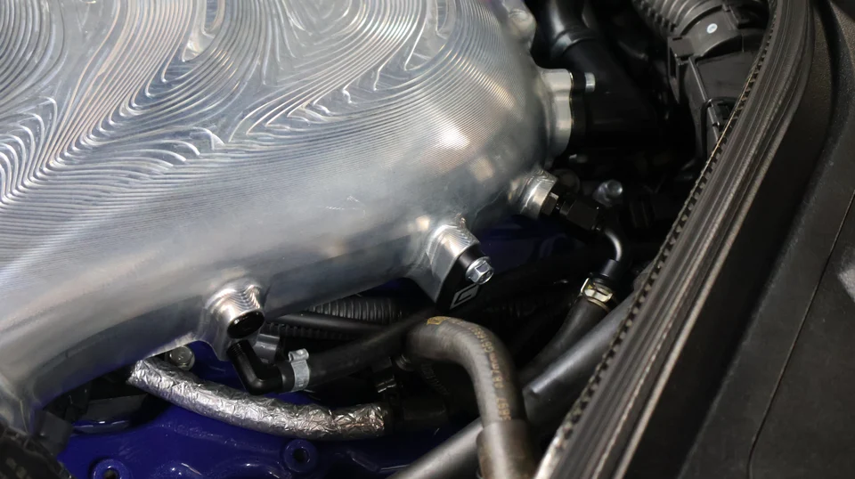 Close-up of a custom billet aluminum intake manifold in a high-performance engine bay.