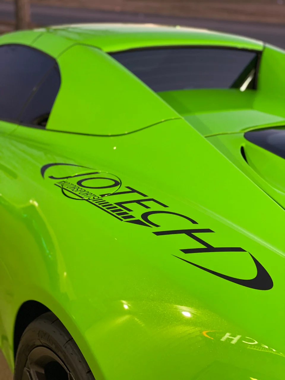 A bright green McLaren supercar with Jotech Motorsports branding on the rear quarter panel.