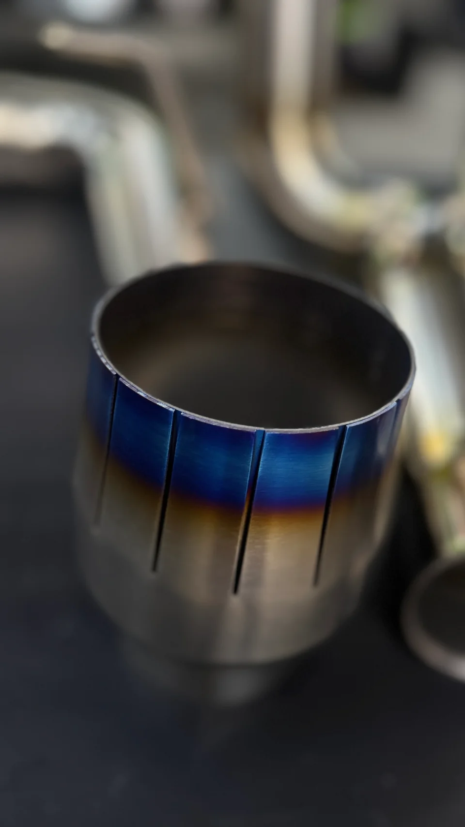 Close-up detail of a burnt titanium exhaust tip, showcasing the blue and gold finish.