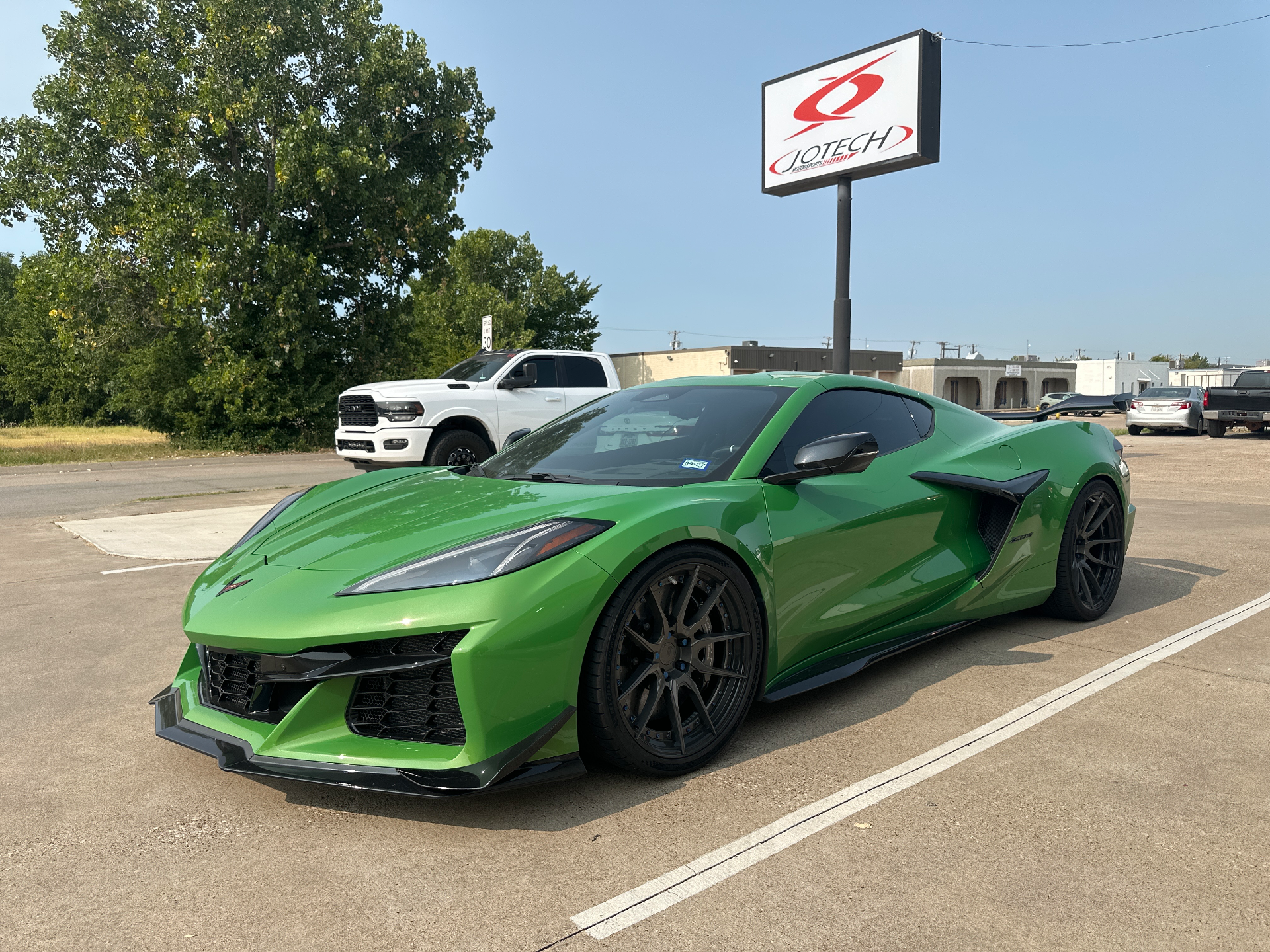 A vibrant green Chevrolet C8 Corvette Z06 with aftermarket wheels and a front splitter parked outside Jotech Motorsports.