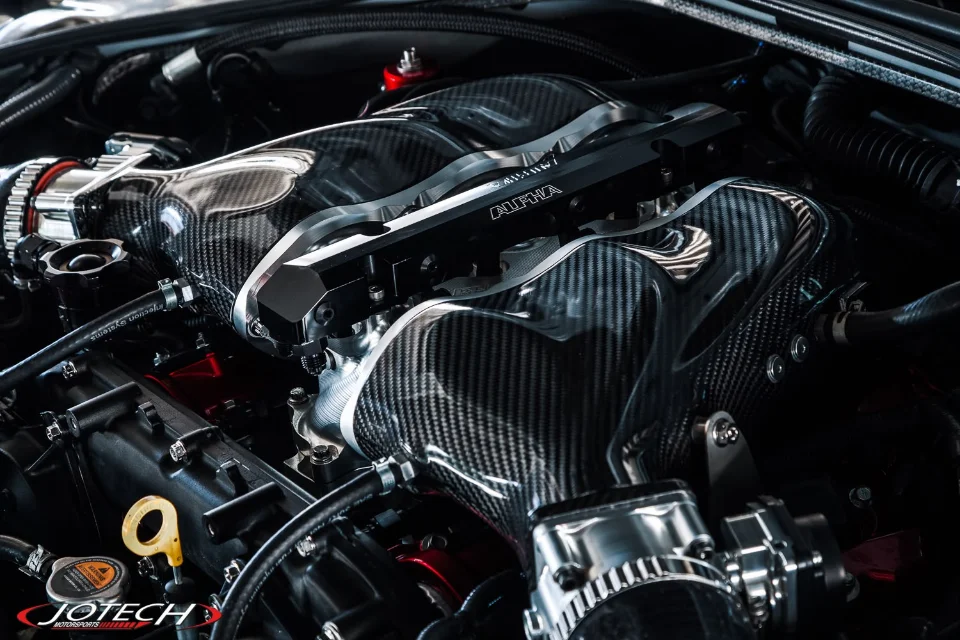 Close-up of a high-performance engine bay featuring carbon fiber intake manifolds and Alpha Performance fuel rails.