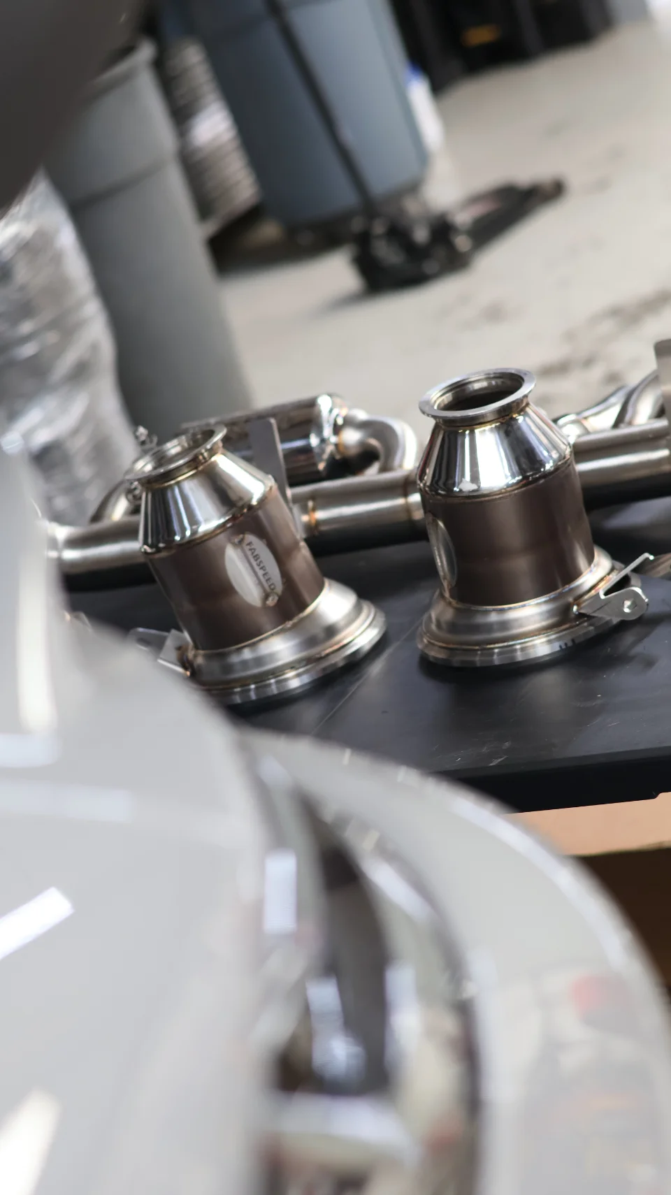 Fabspeed exhaust components, likely catalytic converters or downpipes, laid out in a performance shop.