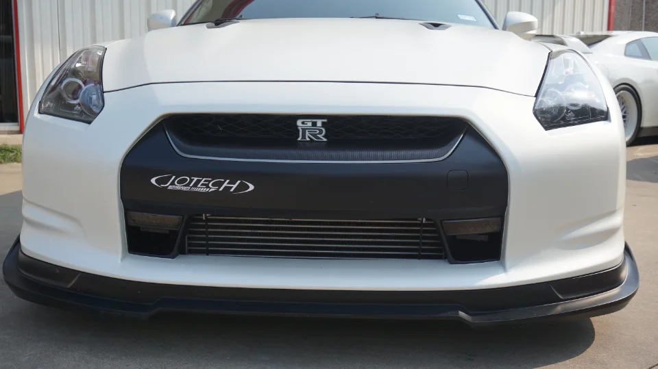 Front view of a white Nissan GT-R with a Jotech logo on the bumper and an aftermarket intercooler visible.