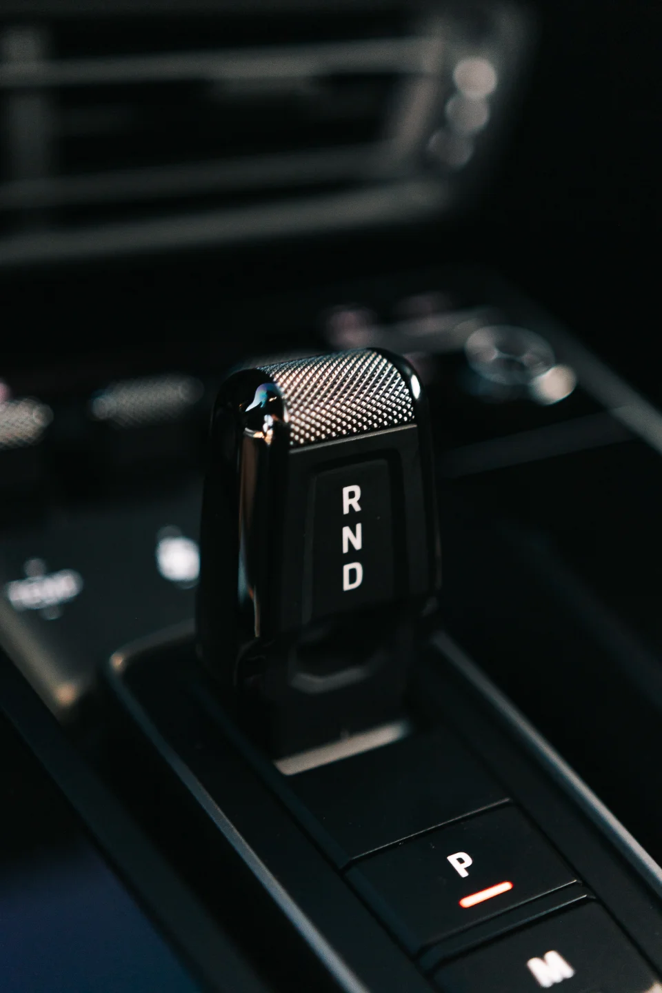 Close-up of a modern car's automatic gear shifter with P, R, N, D selections, highlighting interior detail.