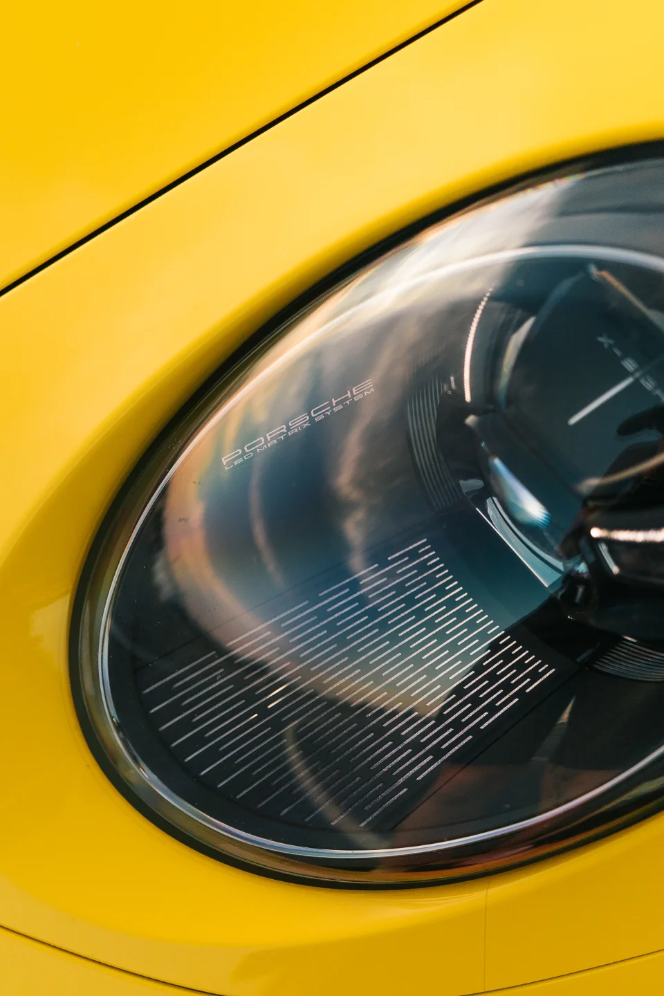 Close-up detail of a yellow Porsche's LED Matrix System headlight, showcasing the intricate lens design.