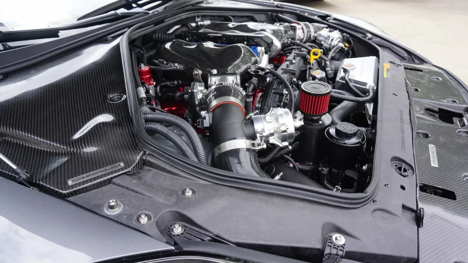 Close-up of a highly modified Nissan GT-R engine bay featuring carbon fiber components and an aftermarket intake system.