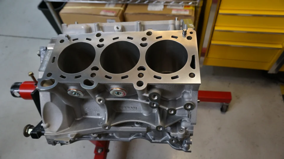 A Nissan engine block on an engine stand in a performance tuning shop, ready for assembly.