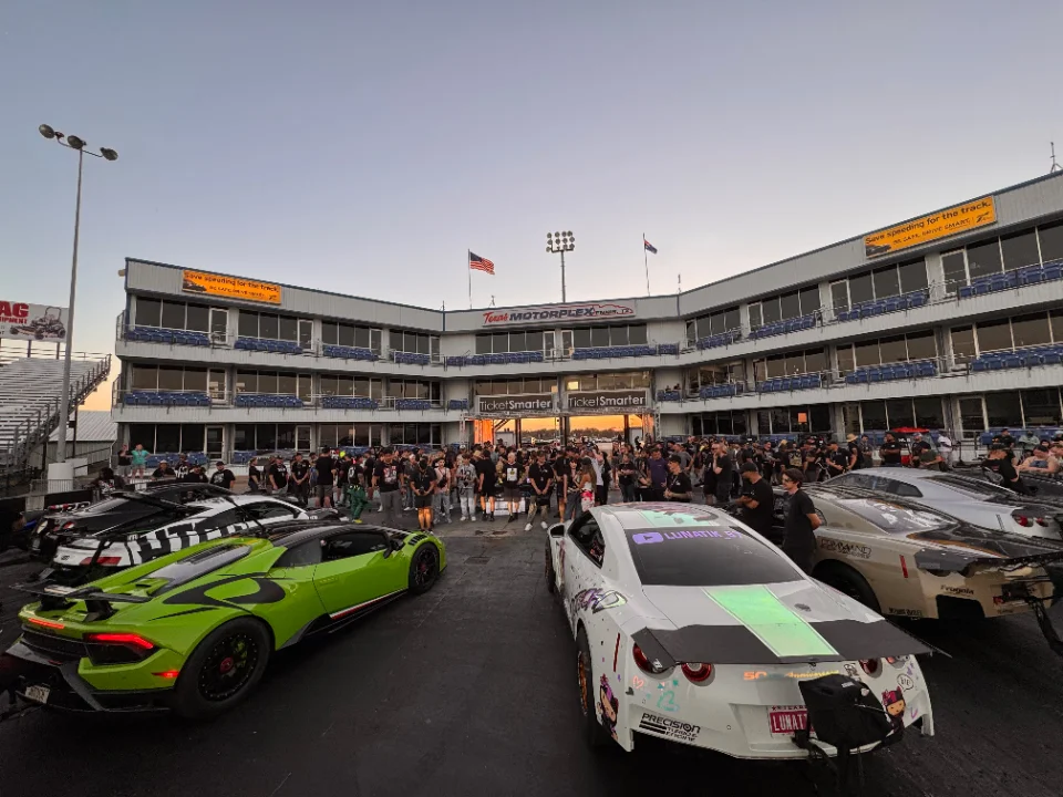 High-performance Lamborghini Huracan and Nissan GT-R race cars at a drag strip event with a crowd at Texas Motorplex.