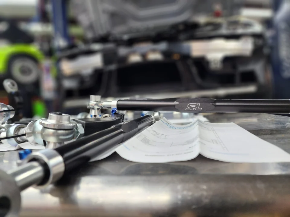 Close-up of SPL Parts adjustable suspension components laid out on a workbench in a performance tuning shop.