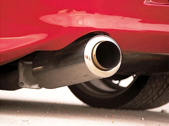 Close-up of a red car's exhaust system with a polished chrome tip.