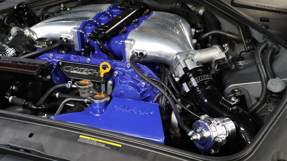 Detailed view of a high-performance Nissan GT-R engine bay with custom blue and silver components, including an intake manifold and turbo system.