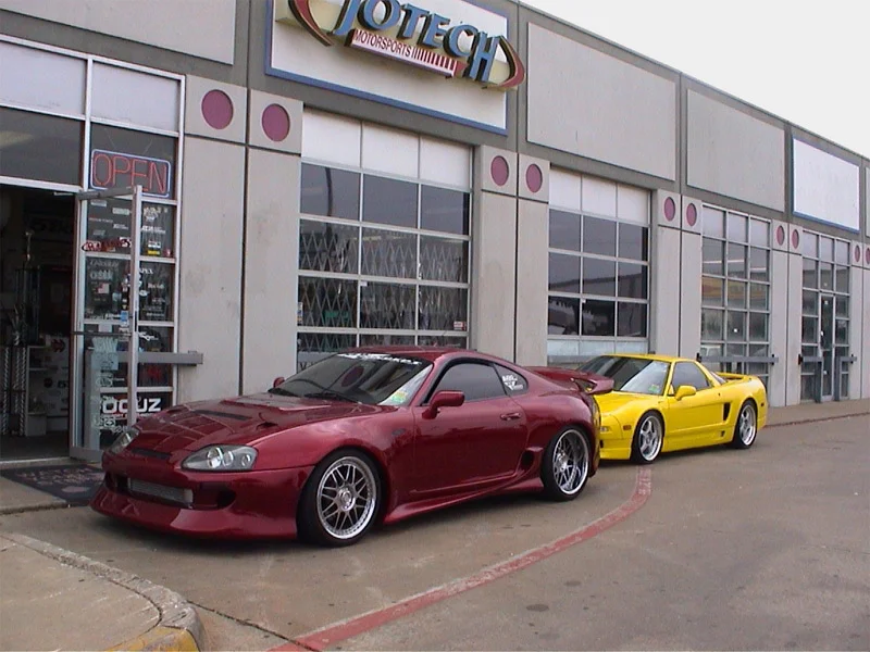 A red Toyota Supra and a yellow Acura NSX parked outside the Jotech Motorsports performance tuning shop.