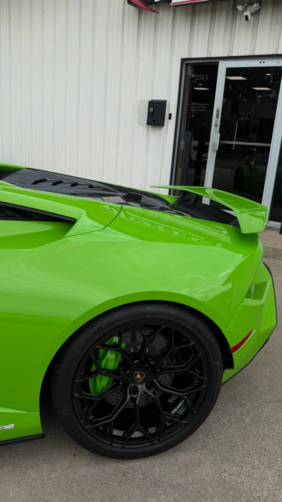 Close-up of a bright green Lamborghini Huracan's rear wheel, black multi-spoke rim, and green brake caliper.