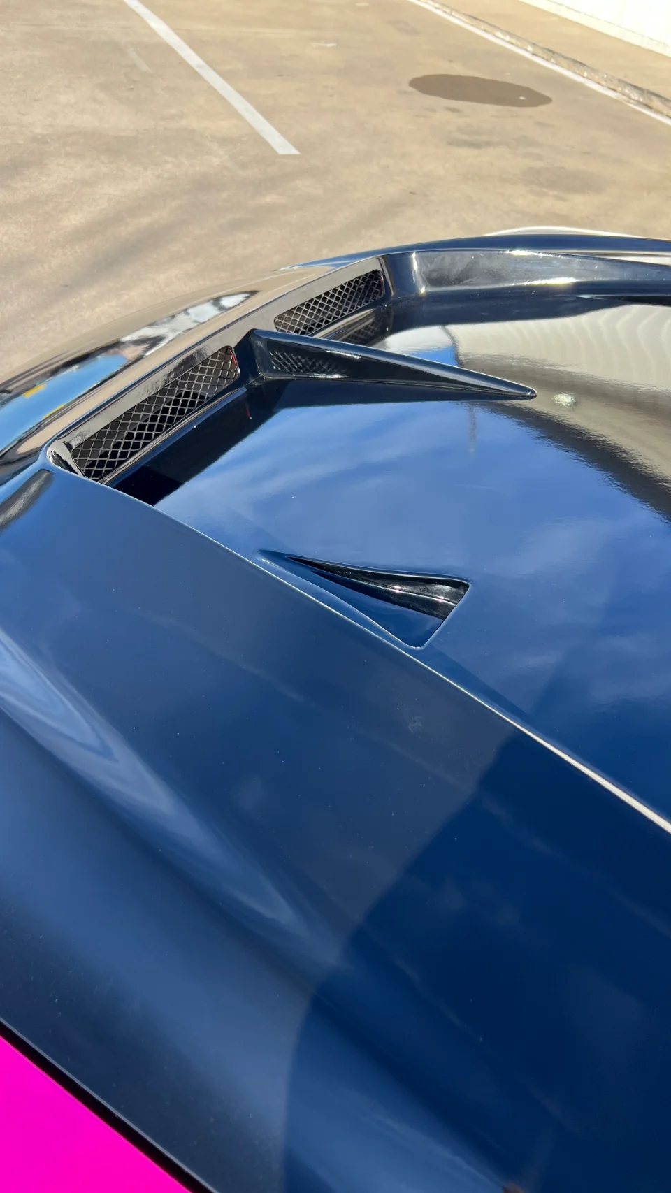 Close-up detail of a car's glossy black hood with performance vents, showcasing the exterior design.
