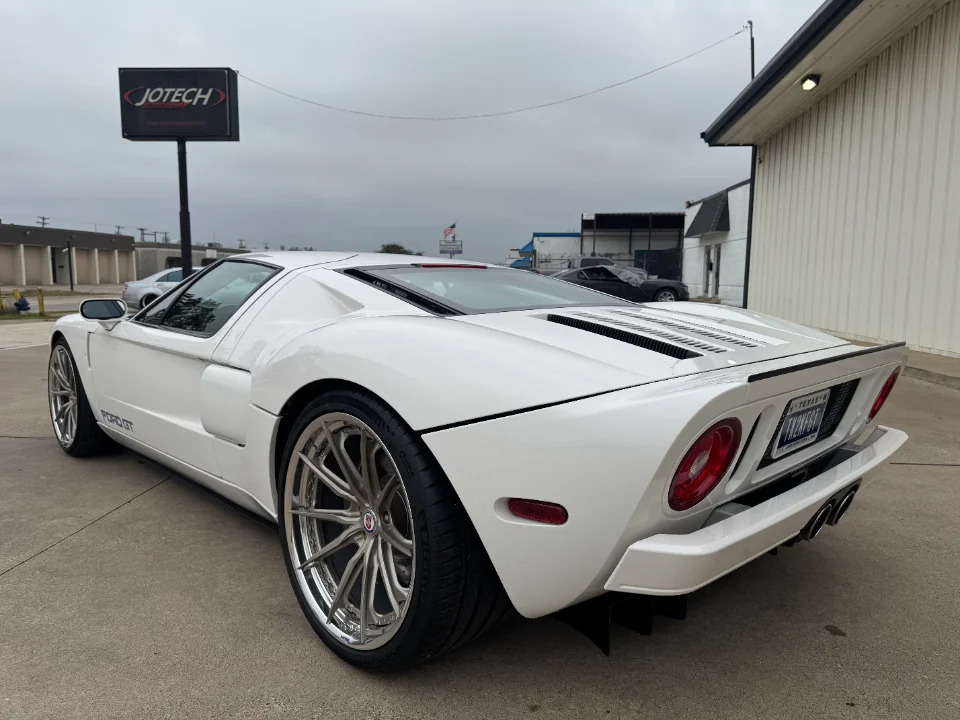 White Ford GT with aftermarket wheels parked outside Jotech Motorsports facility.
