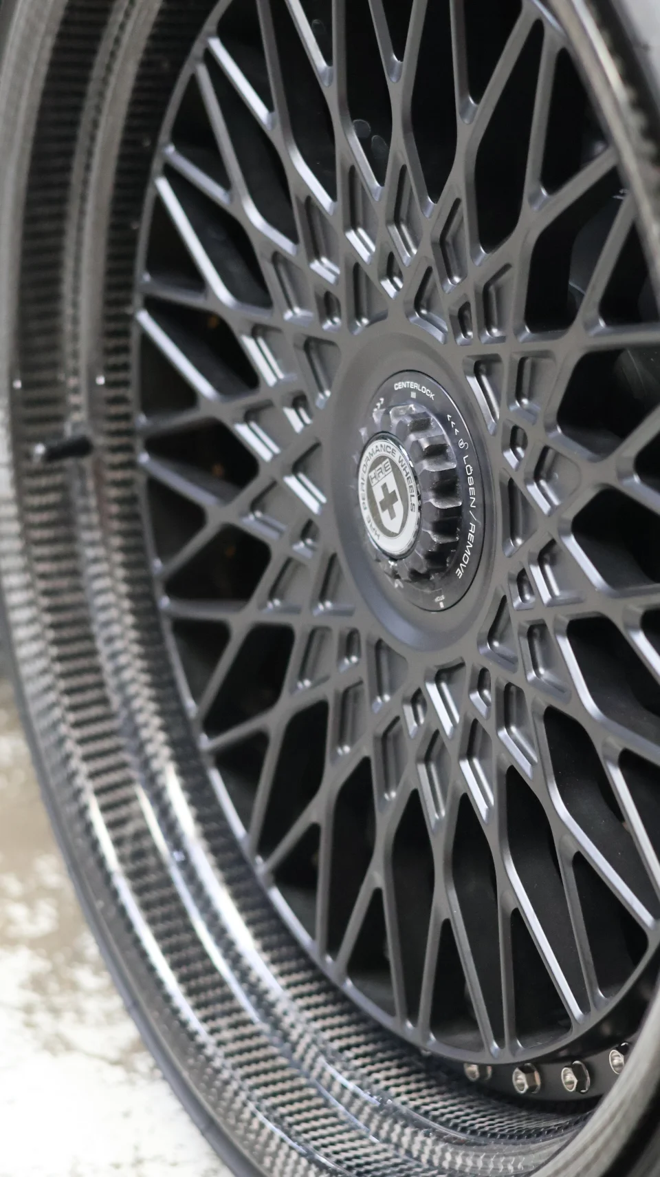 Close-up of an HRE multi-spoke centerlock wheel with a carbon fiber barrel, showcasing intricate design.