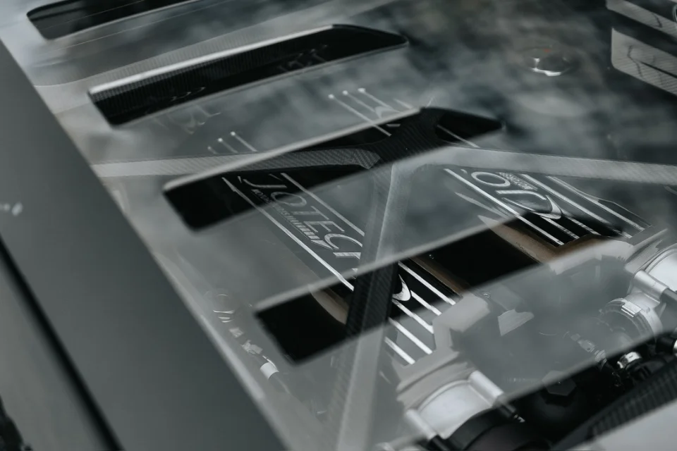 Close-up of a Jotech Motorsports custom engine bay with a clear cover and carbon fiber accents, showcasing the performance engine.