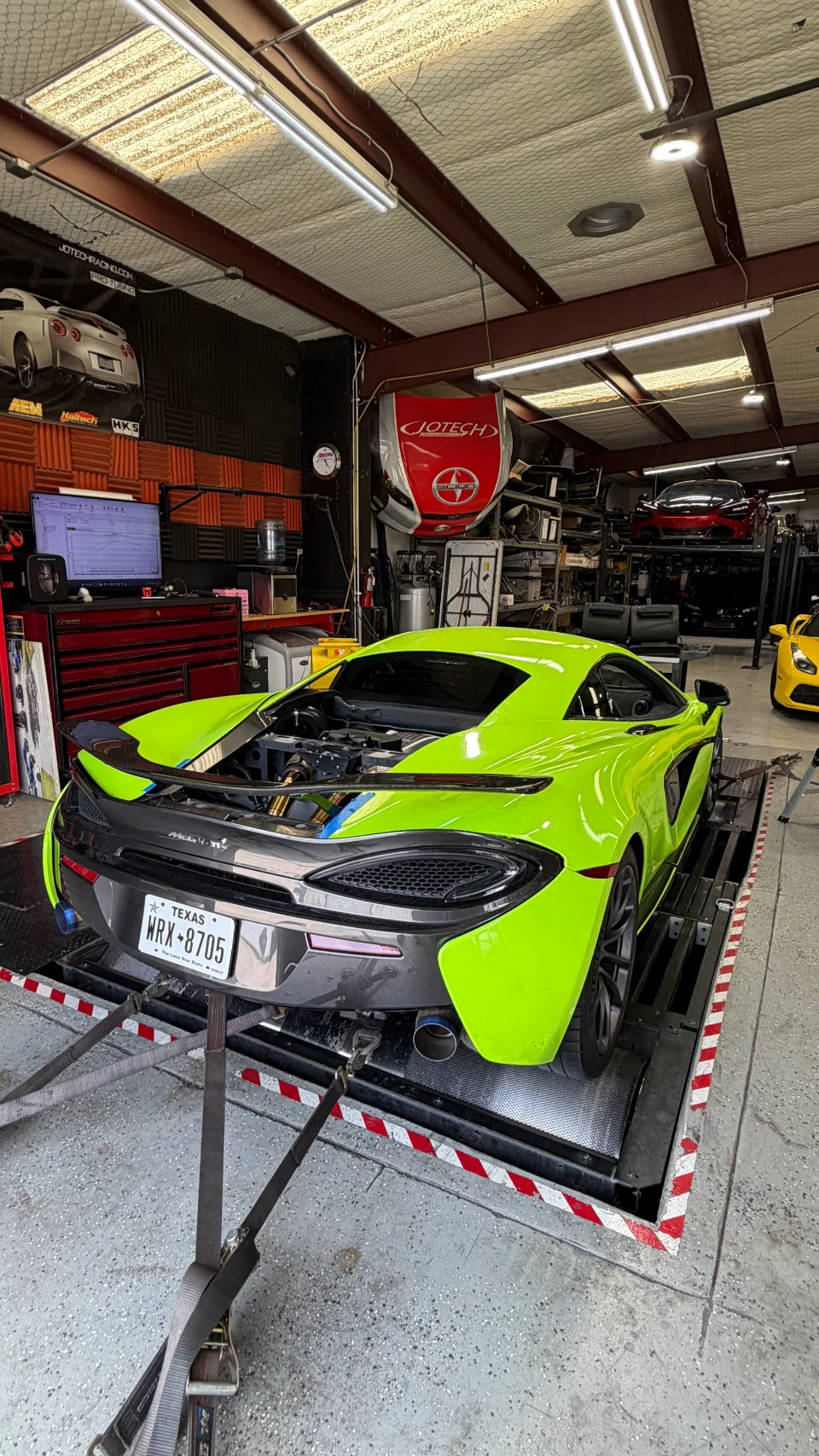 A lime green McLaren 570S strapped to a dynamometer at Jotech Motorsports for performance tuning.