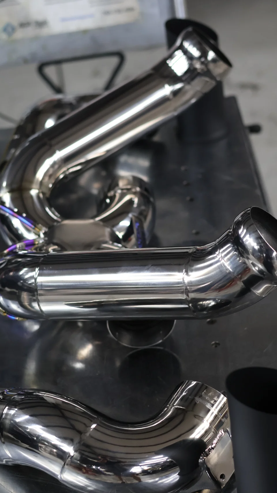 Close-up of polished stainless steel exhaust pipes with visible welds, ready for installation.