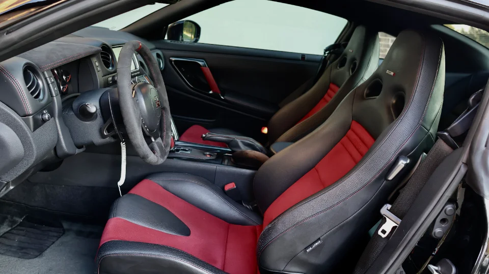 Detailed view of a Nissan GT-R interior with black and red Nismo seats and an Alcantara steering wheel.