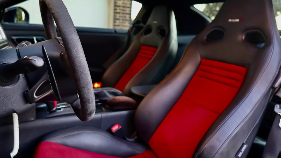Close-up of a Nissan GT-R Nismo interior featuring red and black racing seats and an Alcantara steering wheel.
