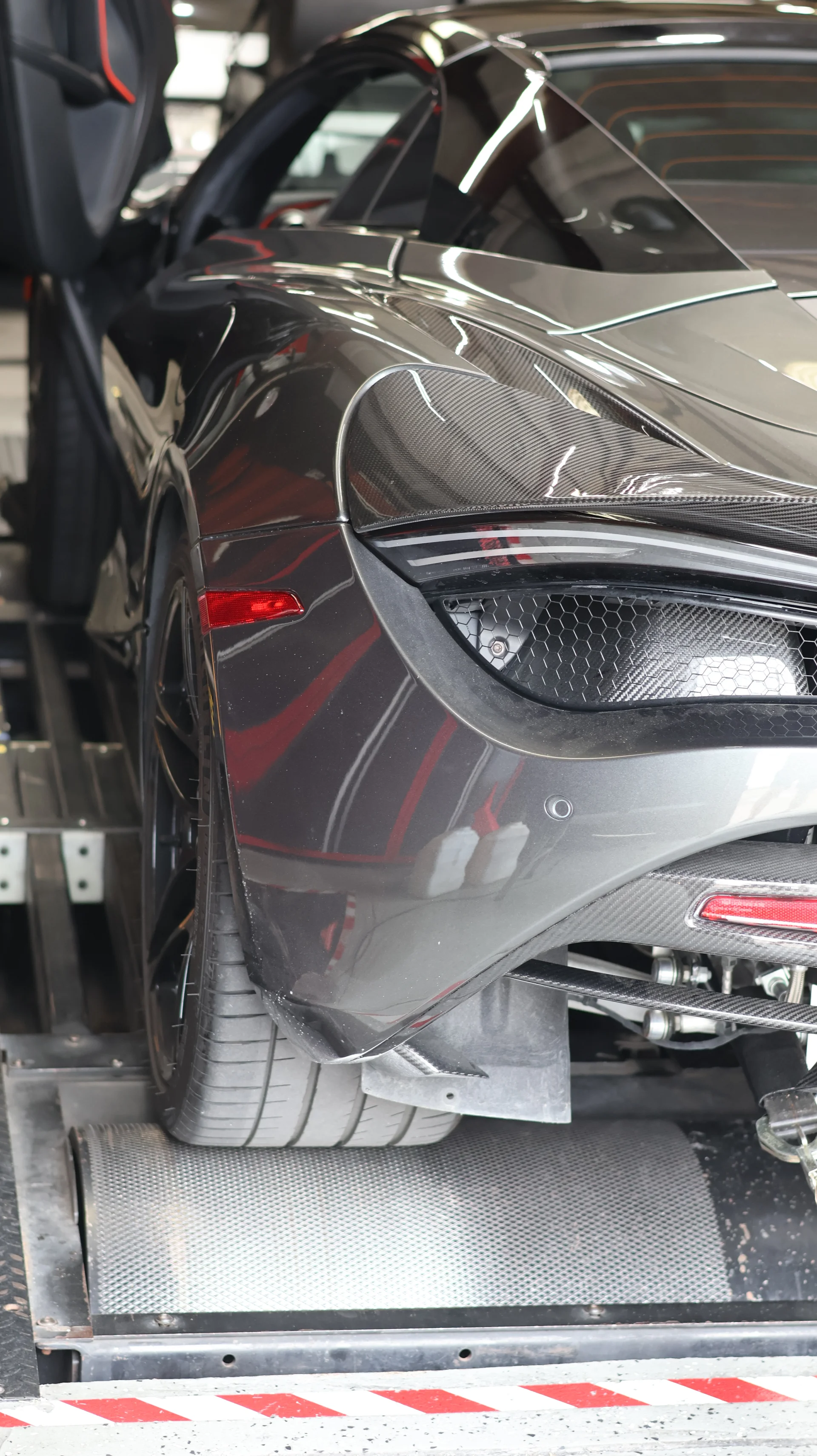 A grey McLaren 720S sports car strapped to a dynamometer, with its rear wheel on the rollers during performance testing.