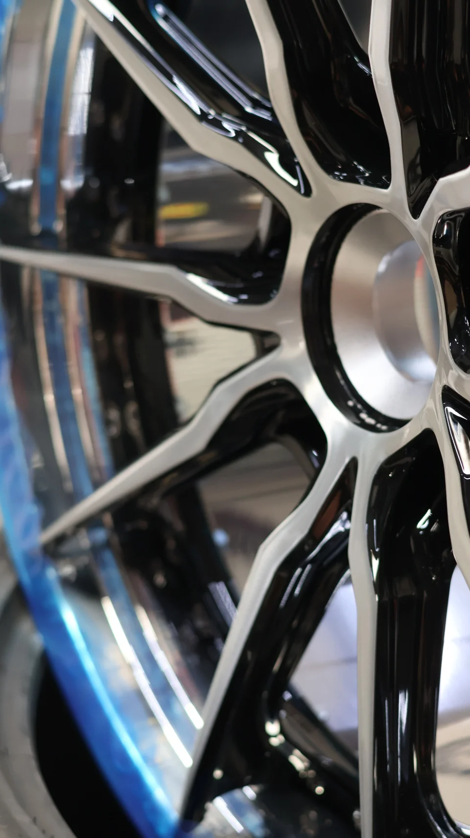 Close-up detail of a multi-spoke black and silver aftermarket wheel with a blue protective wrap on the tire.