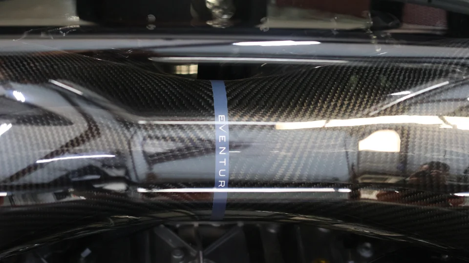 Close-up of an Eventuri carbon fiber intake tube in an engine bay.