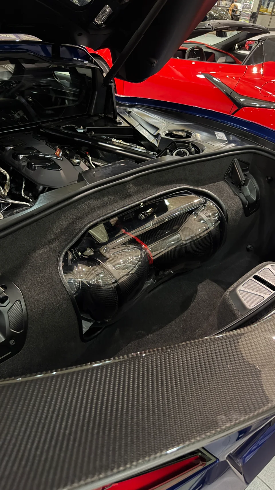 Close-up of a C8 Corvette engine bay featuring a carbon fiber induction system and engine cover.