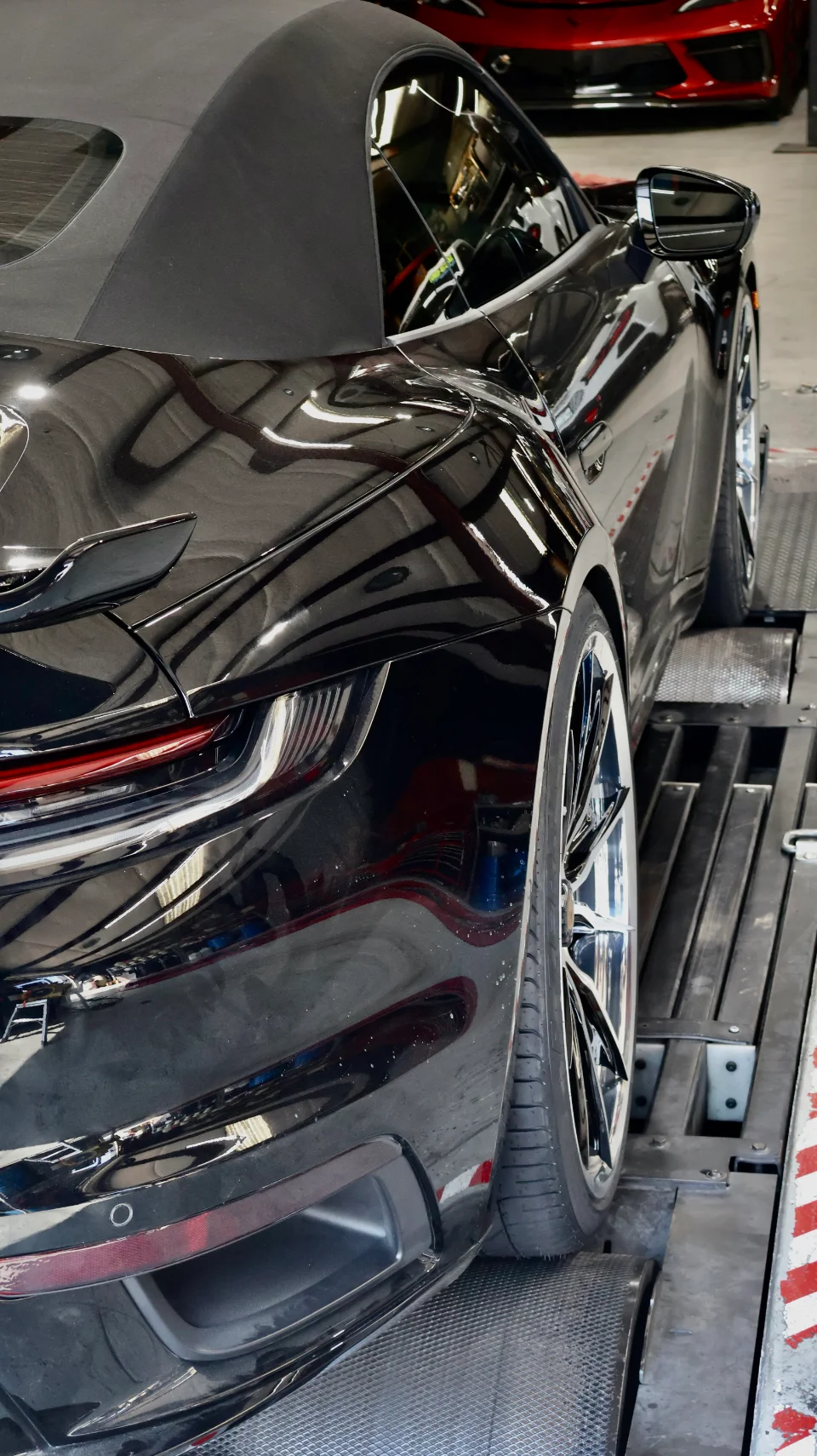 A black Porsche 911 convertible is strapped down on a dynamometer for performance testing.
