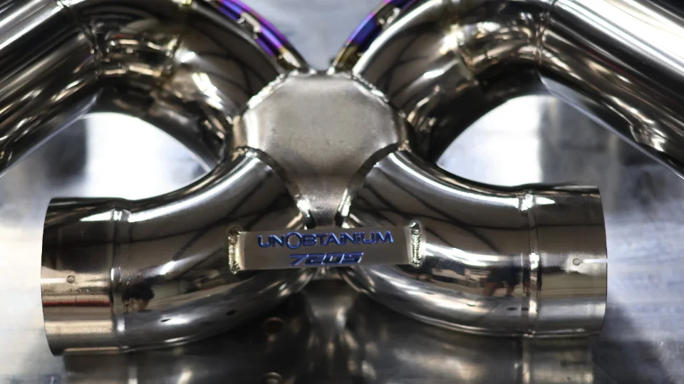 Close-up of a polished titanium exhaust component with 'UNObtanium 720S' branding.