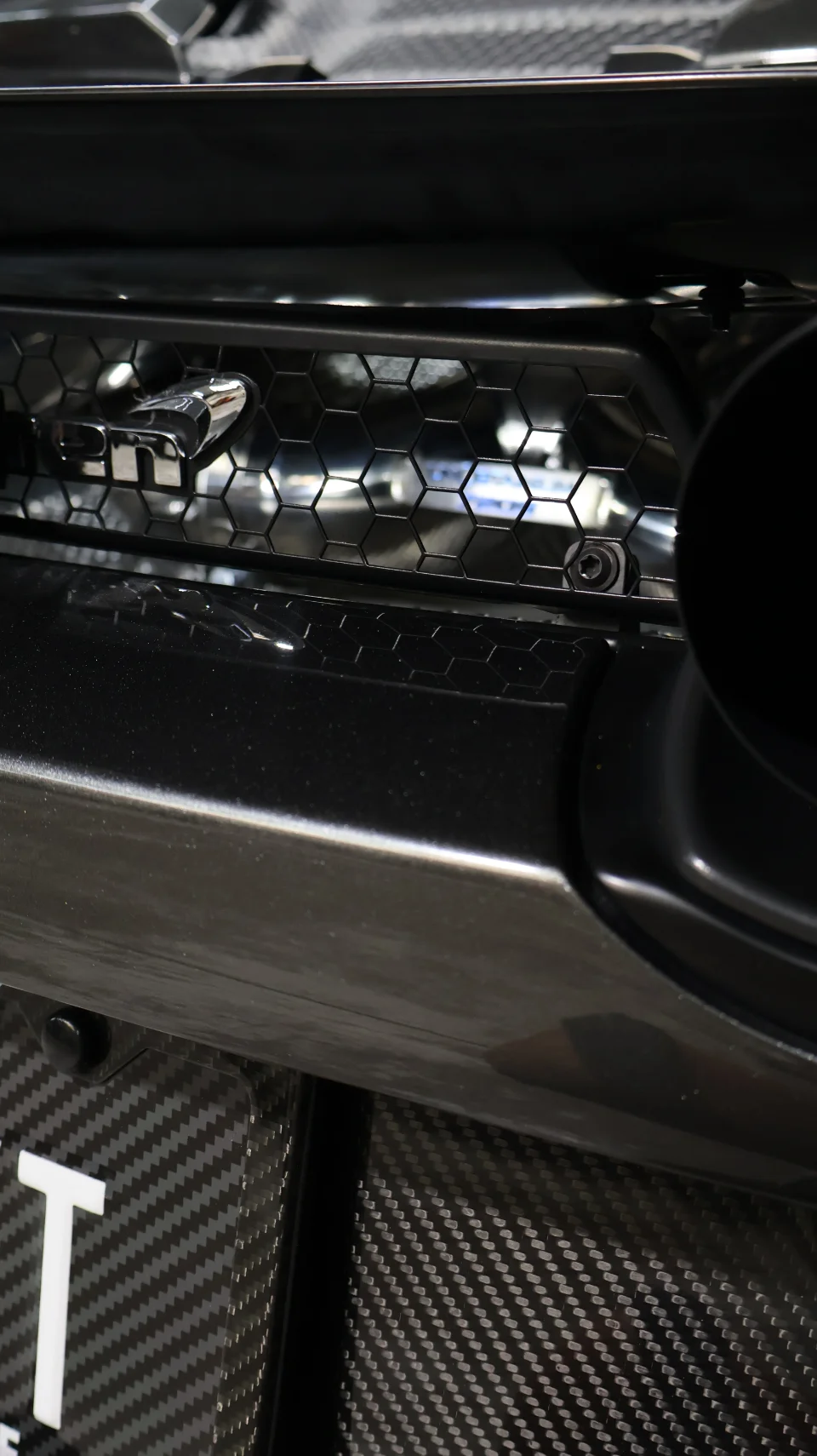 Close-up detail of a Nissan GT-R's carbon fiber rear diffuser, honeycomb grille, and exhaust tip.