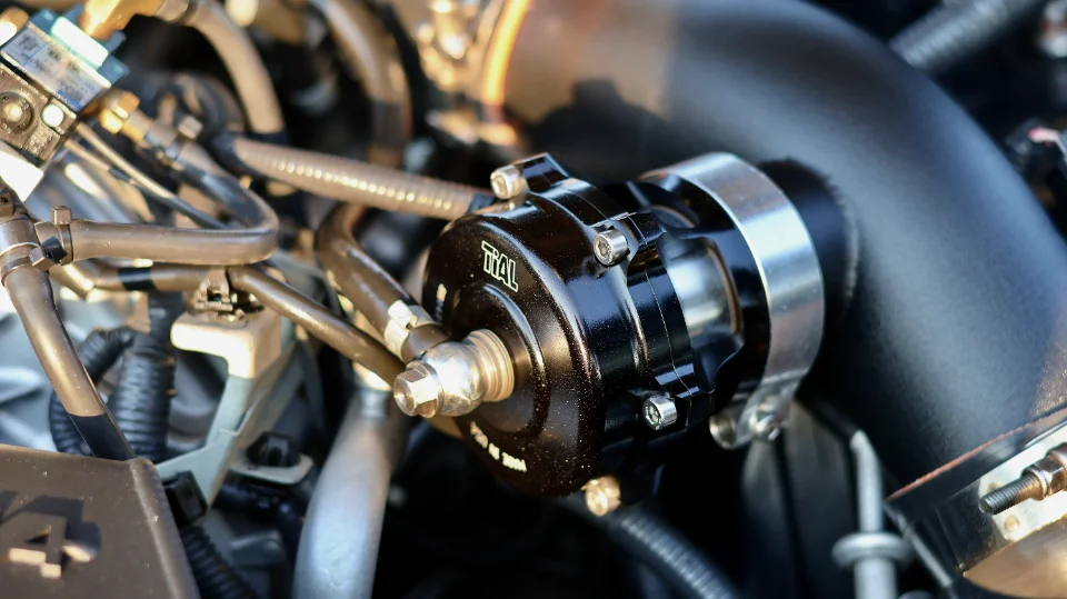 Close-up of a black Tial blow-off valve installed in a performance car's engine bay, connected to boost piping.